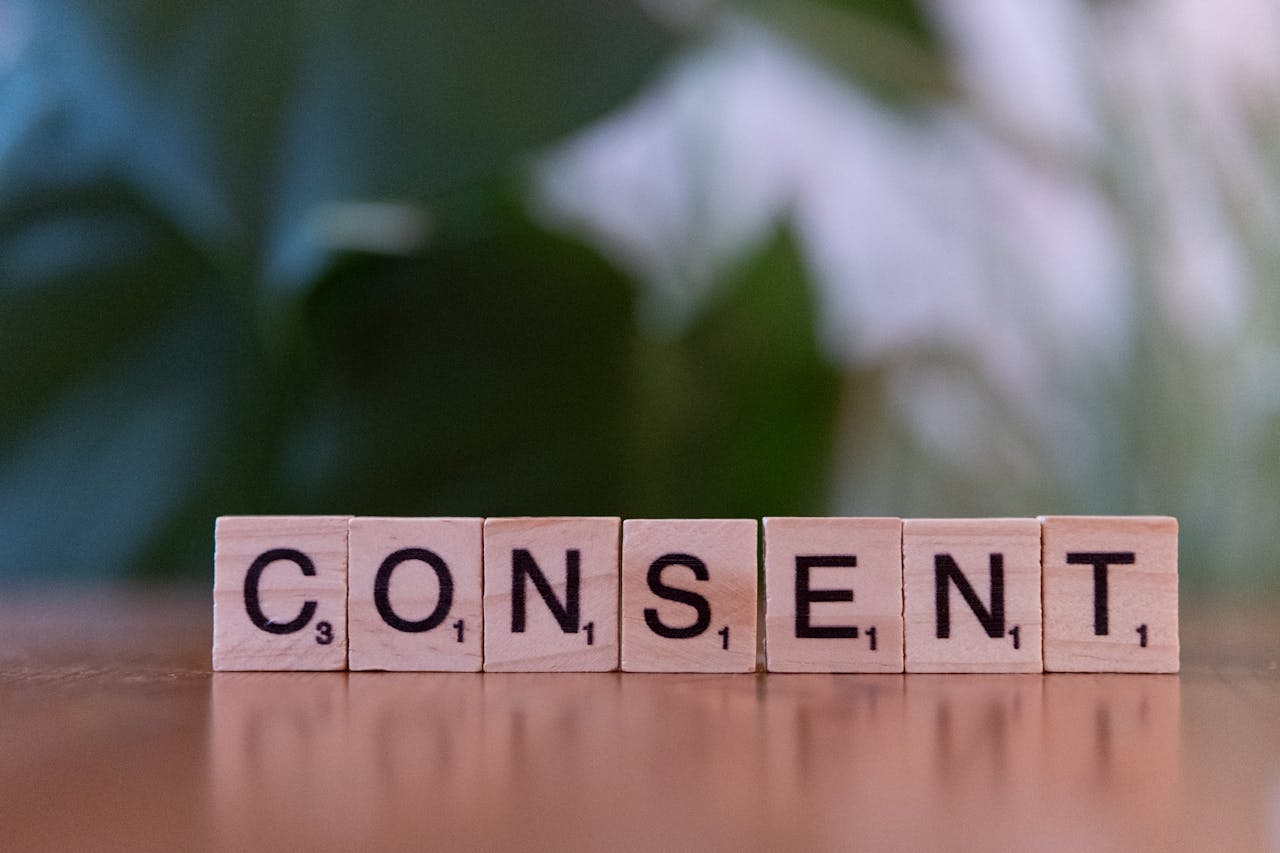 Close-up of Scrabble tiles spelling 'Consent' on a wooden surface, focusing on ethics and communication.